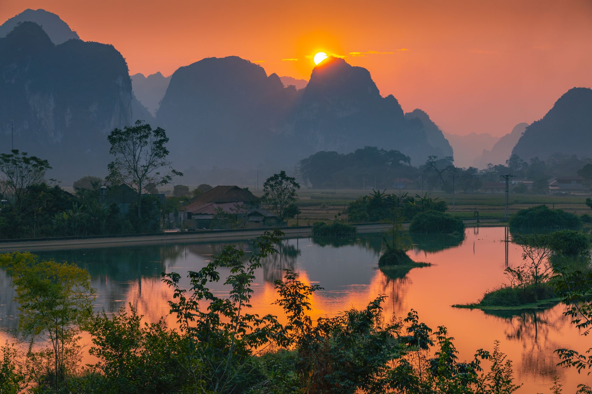 Serene sunset view over Lạng Sơn's majestic mountains reflecting in a tranquil lake.