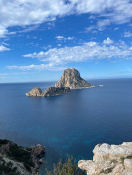 A breathtaking view of the iconic Es Vedrà island off the coast of Ibiza, under a clear blue sky.