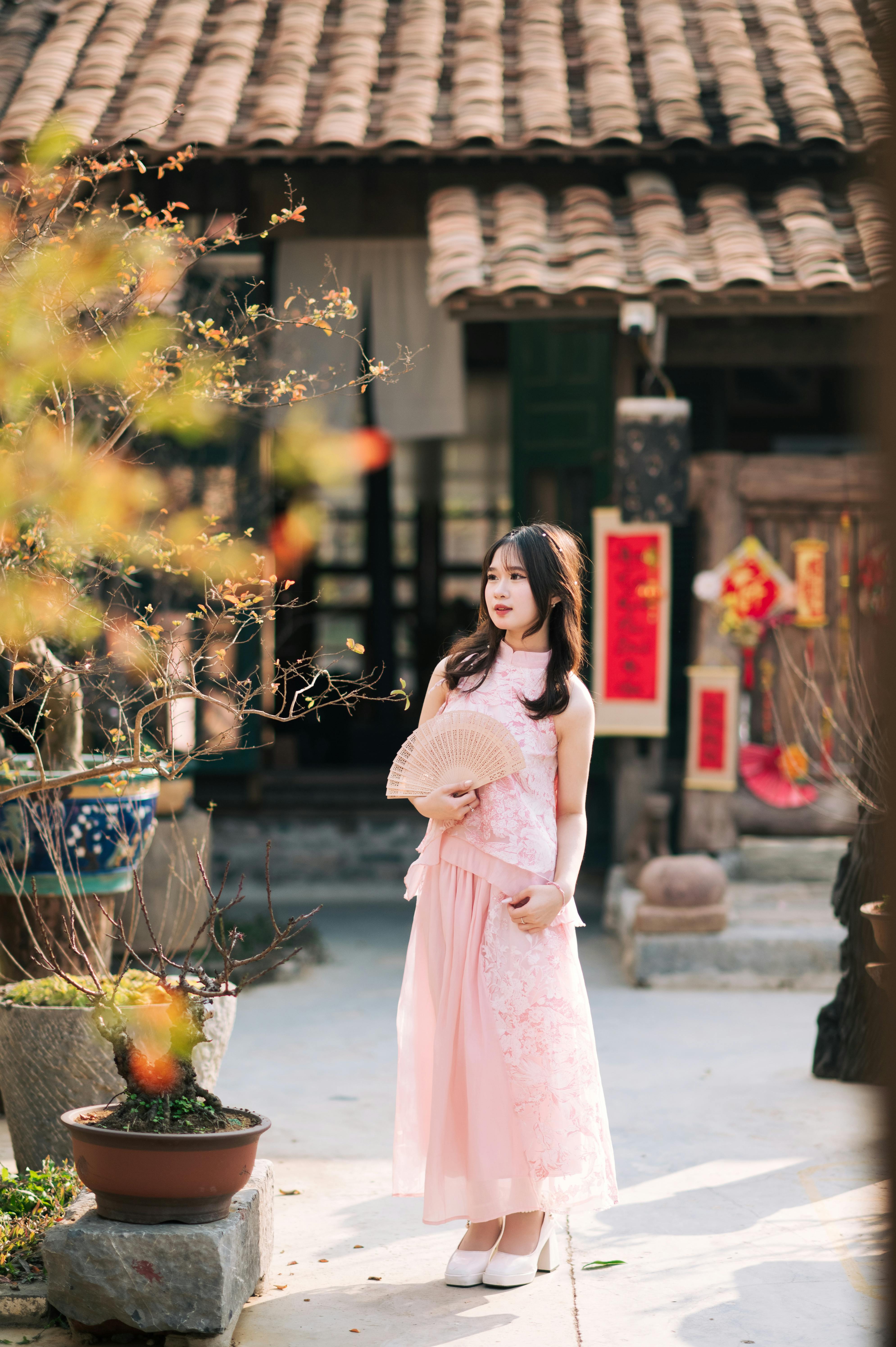 A woman in a pink traditional dress holding a fan at a historic location in Lạng Sơn, Vietnam.