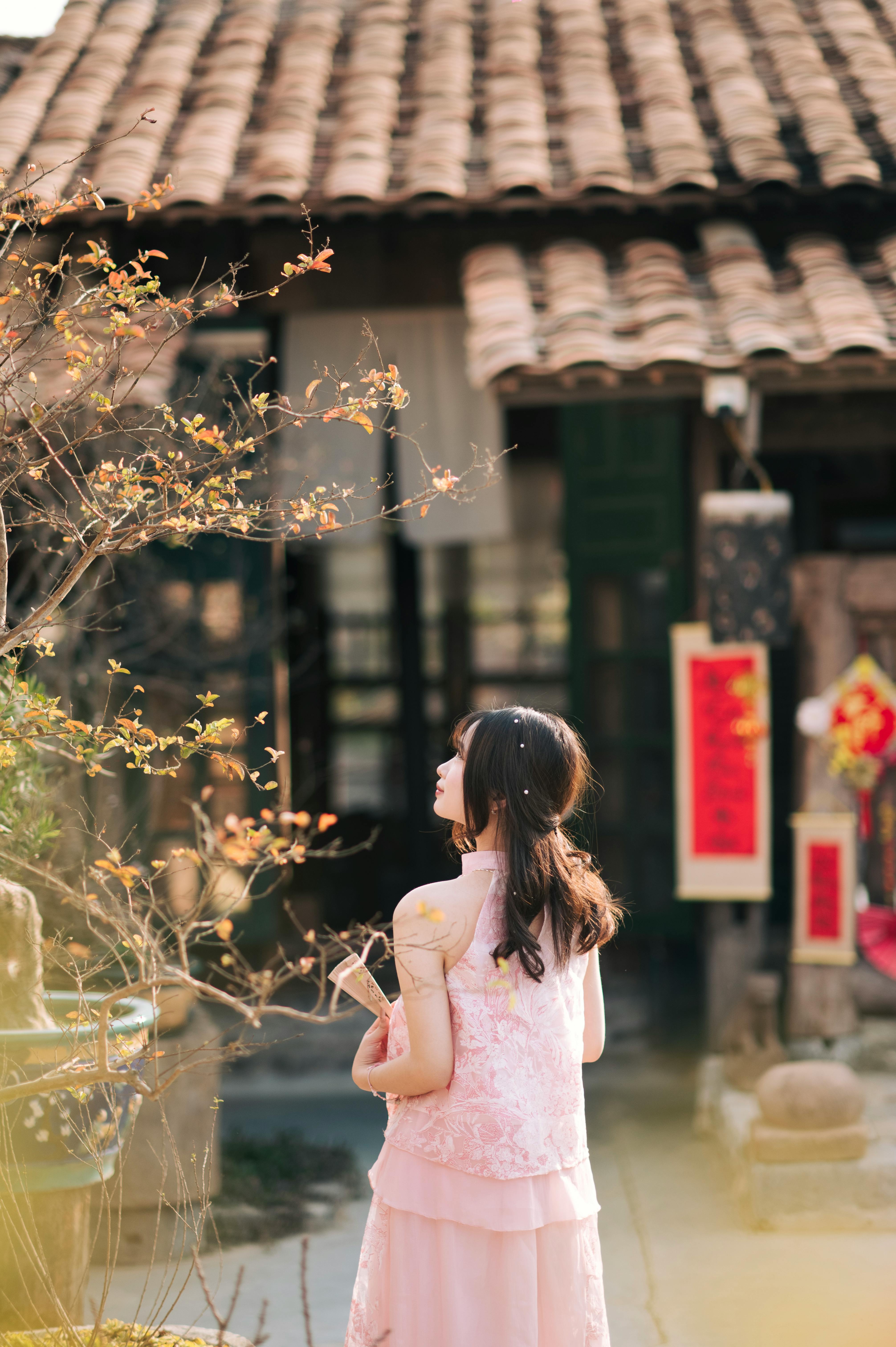 Young woman in pink dress celebrating Tet in a Vietnamese courtyard.