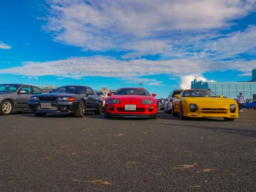 Free A vibrant collection of iconic JDM cars under a clear blue sky at a car meet. Stock Photo