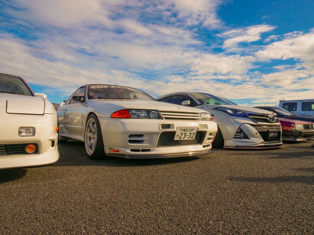 Free A lineup of classic JDM cars featuring a Nissan Skyline R32 at an outdoor car meet. Stock Photo