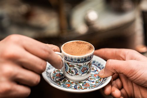Free Close-up of Turkish coffee in a floral patterned cup being handed over by two people. Stock Photo