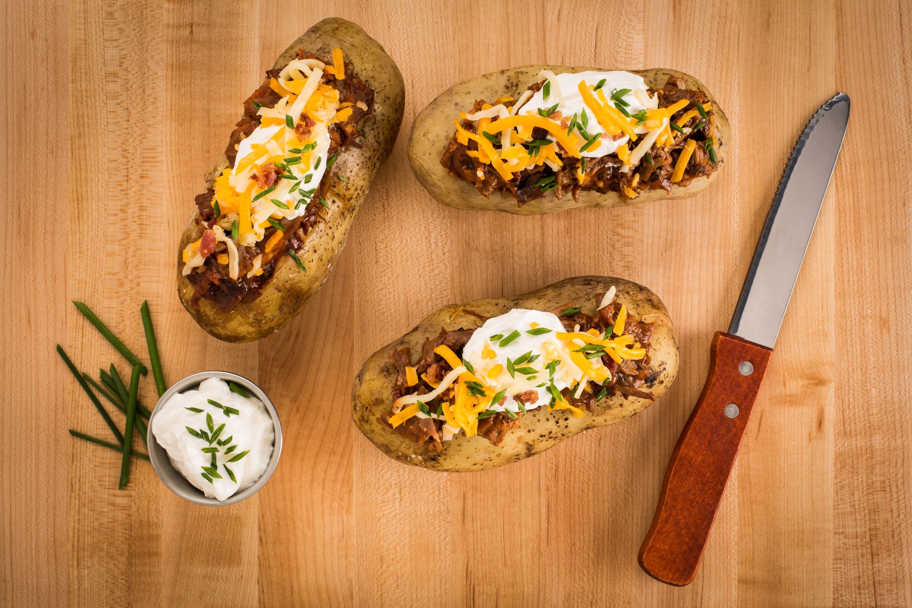 Grilled loaded baked potatoes served with sour cream and bacon