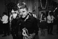 A festive indoor celebration with people dancing in elegant attire.