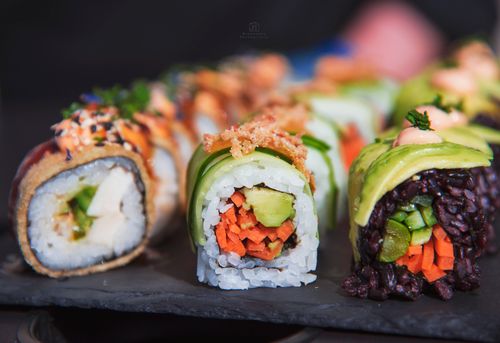 Free Colorful sushi rolls featuring fresh vegetables on a slate platter. Stock Photo