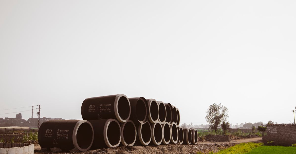 Stack of Large Concrete Pipes in Rural Field · Free Stock Photo