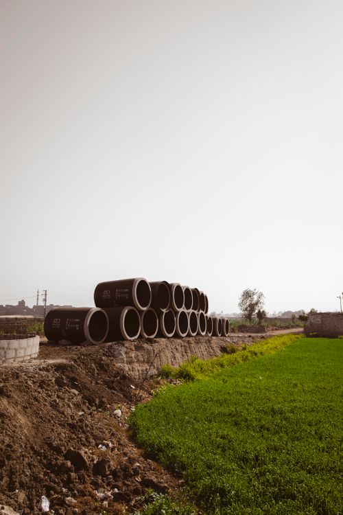 Stack of Large Concrete Pipes in Rural Field · Free Stock Photo