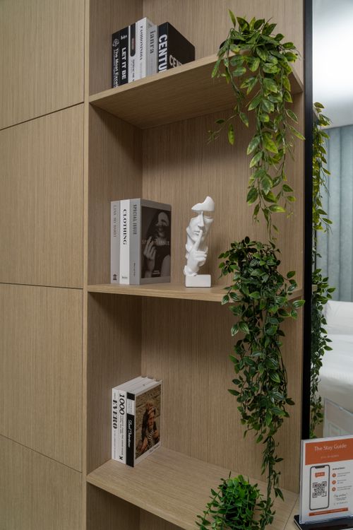 Free Stylish wooden bookshelf featuring books, plants, and artistic decor in Dubai setting. Stock Photo