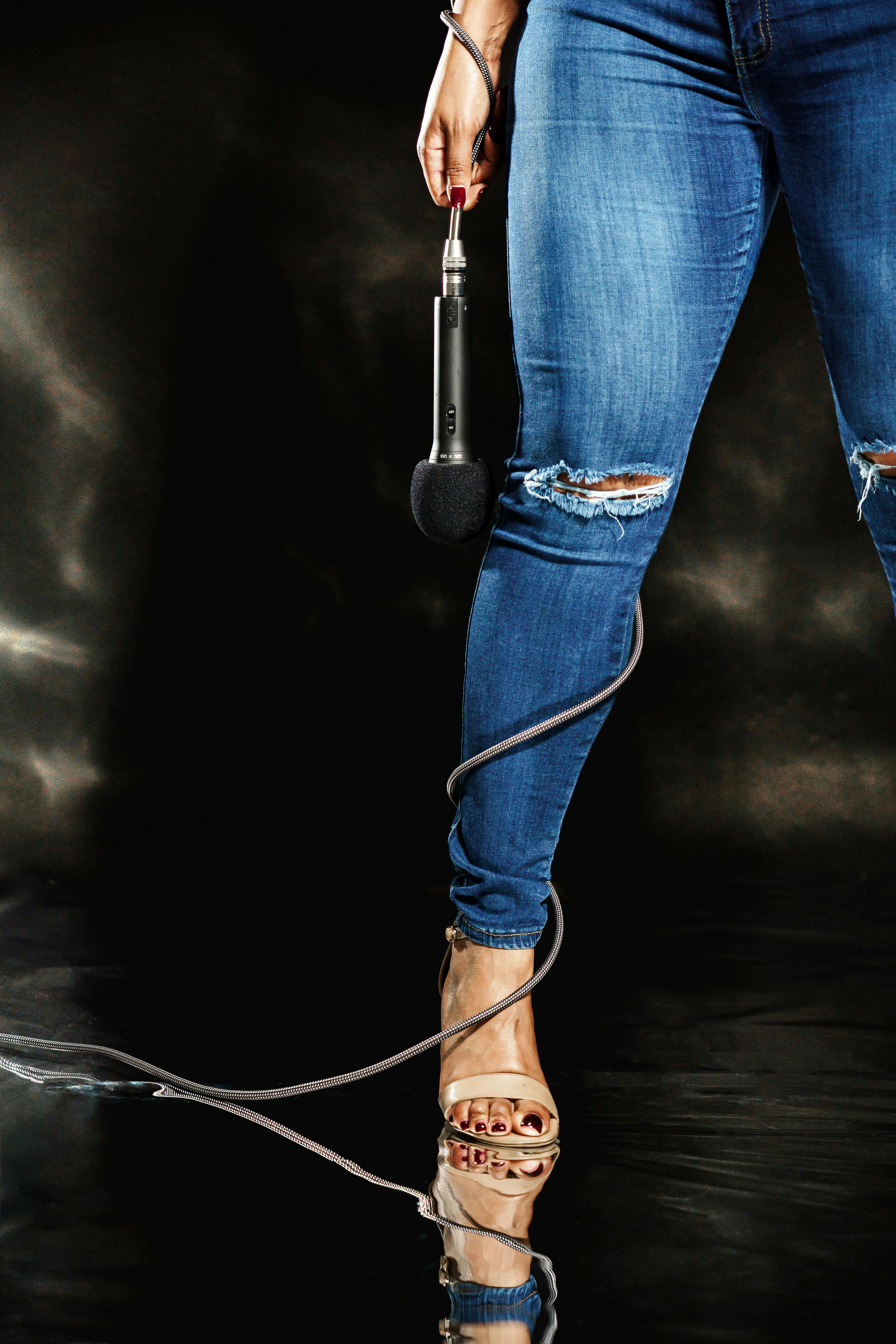Woman in ripped jeans holding microphone showcasing style and elegance in New Orleans.