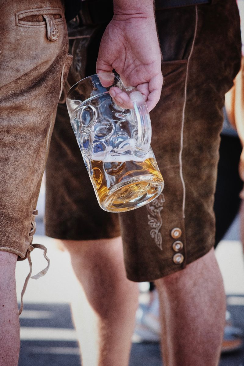 Man wearing lederhosen holding a beer stein at a festival