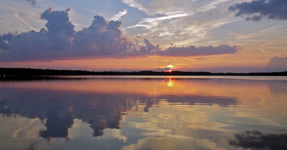Tranquil sunset over a calm lake with dramatic cloud reflections.