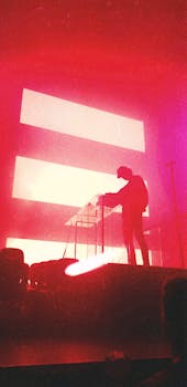 Silhouetted DJ performs on stage with vibrant neon red lights at a live concert in Amsterdam.