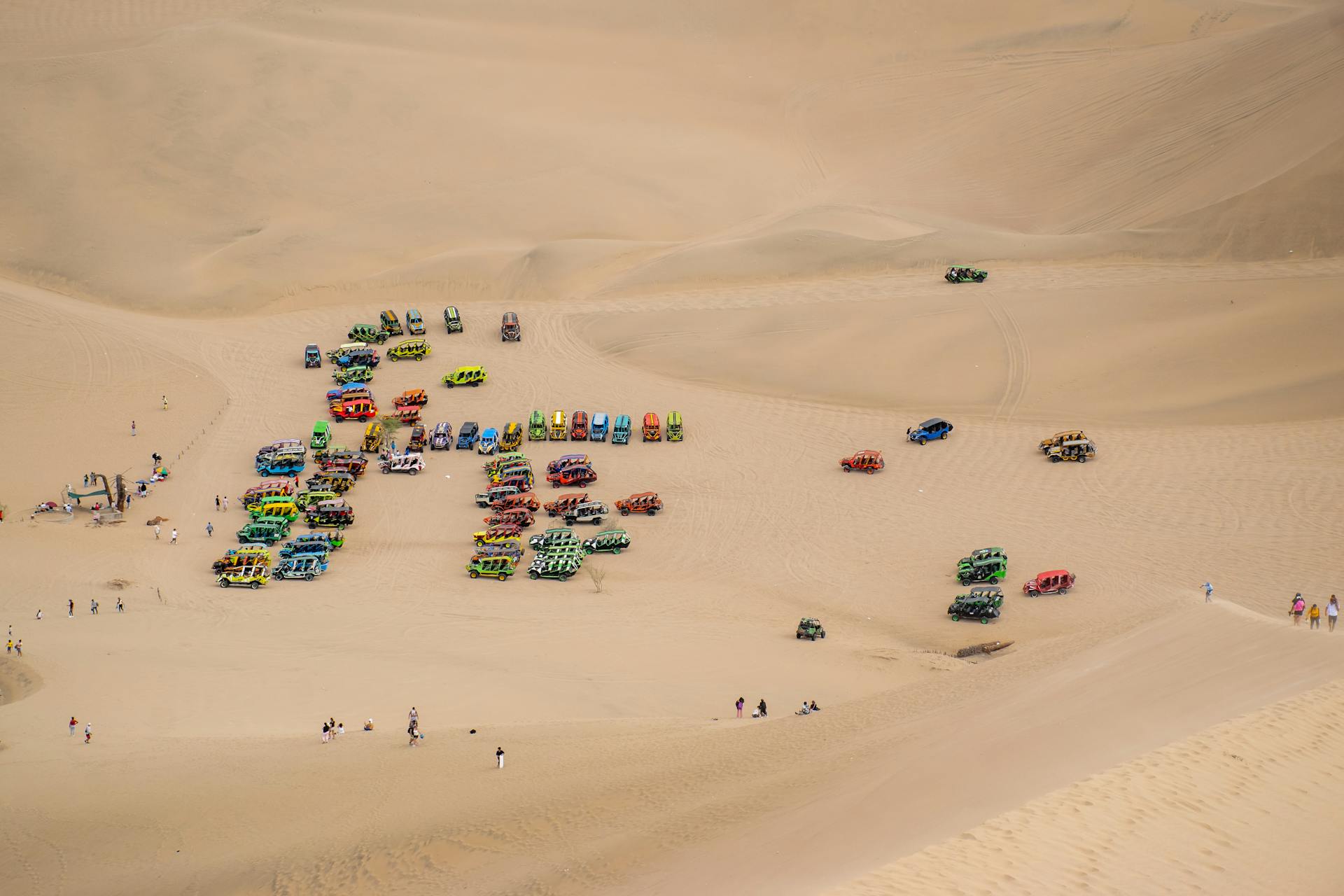 Colorful dune buggies scattered across the vast sand dunes of Ica, Peru, capturing adventure and exploration.