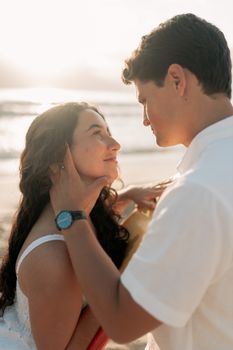A romantic couple gazing into each other's eyes on a serene beach at sunset, symbolizing love.