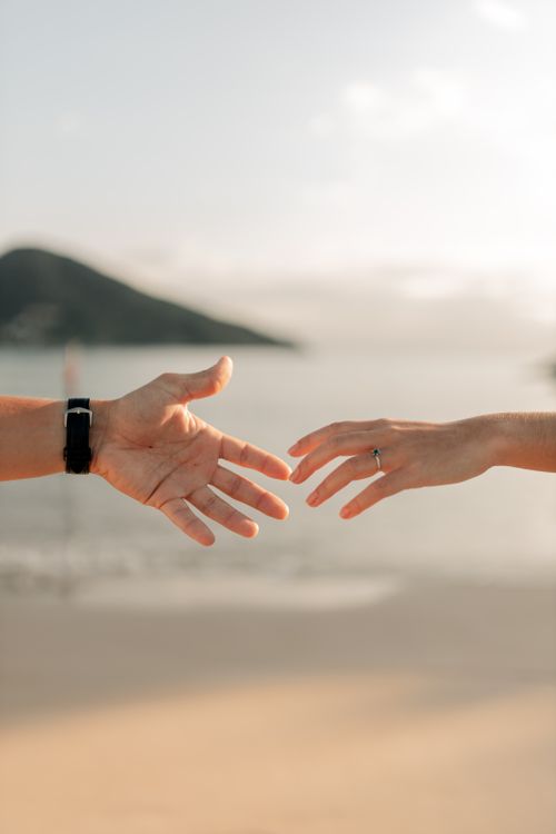 Free Two hands reaching out against a serene beach backdrop, symbolizing connection. Stock Photo