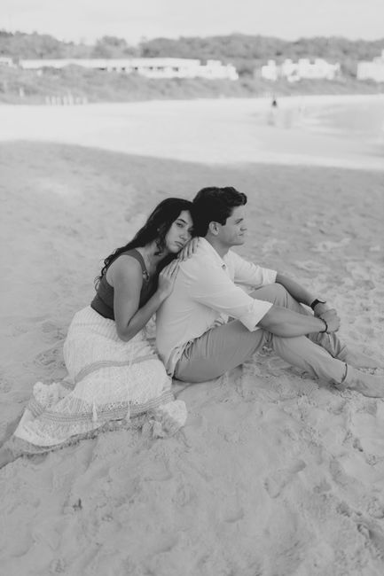 A couple sitting on a sandy beach, embracing in a peaceful and serene monochrome setting.