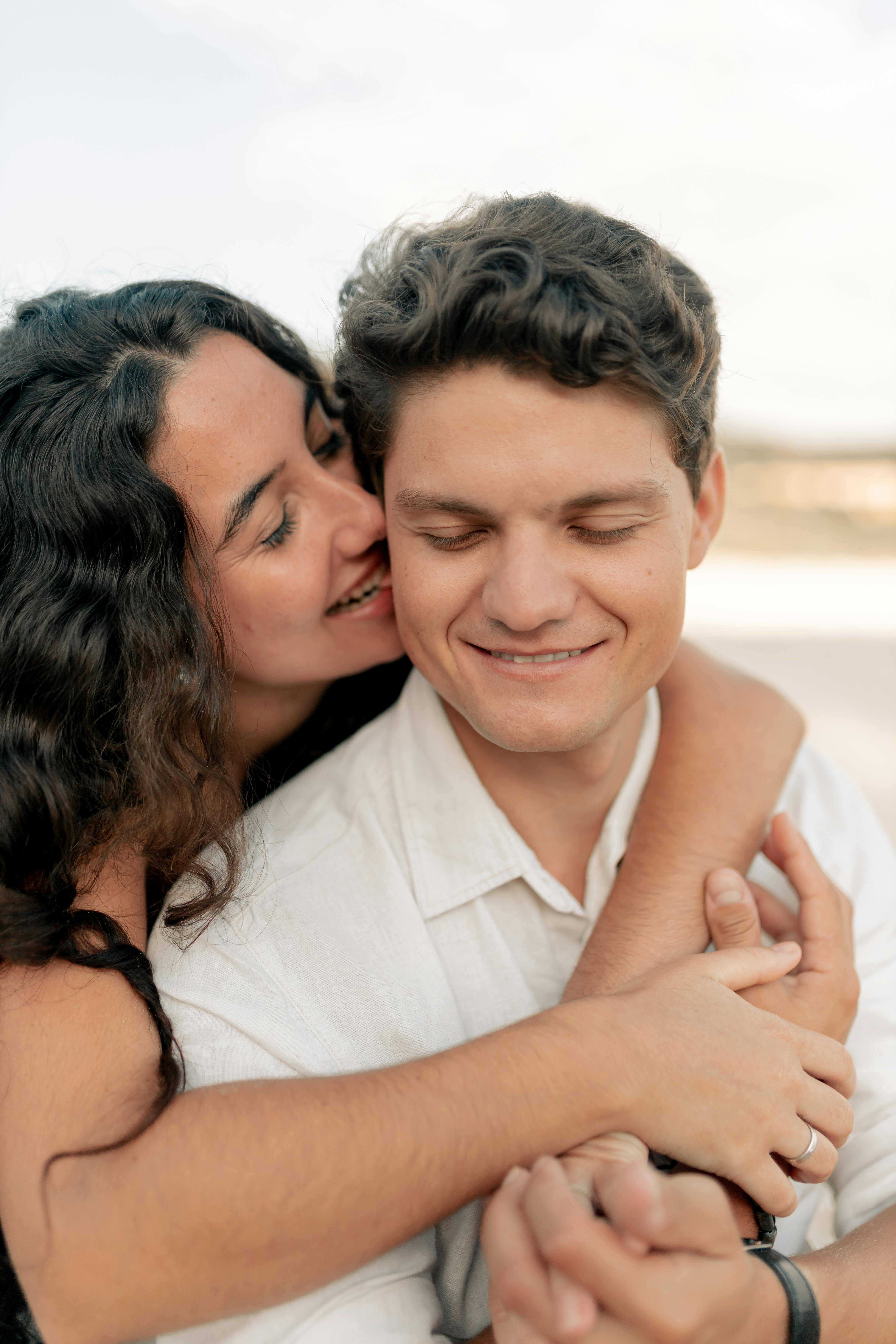 A young couple shares an intimate moment outdoors during sunset, exuding love and happiness.