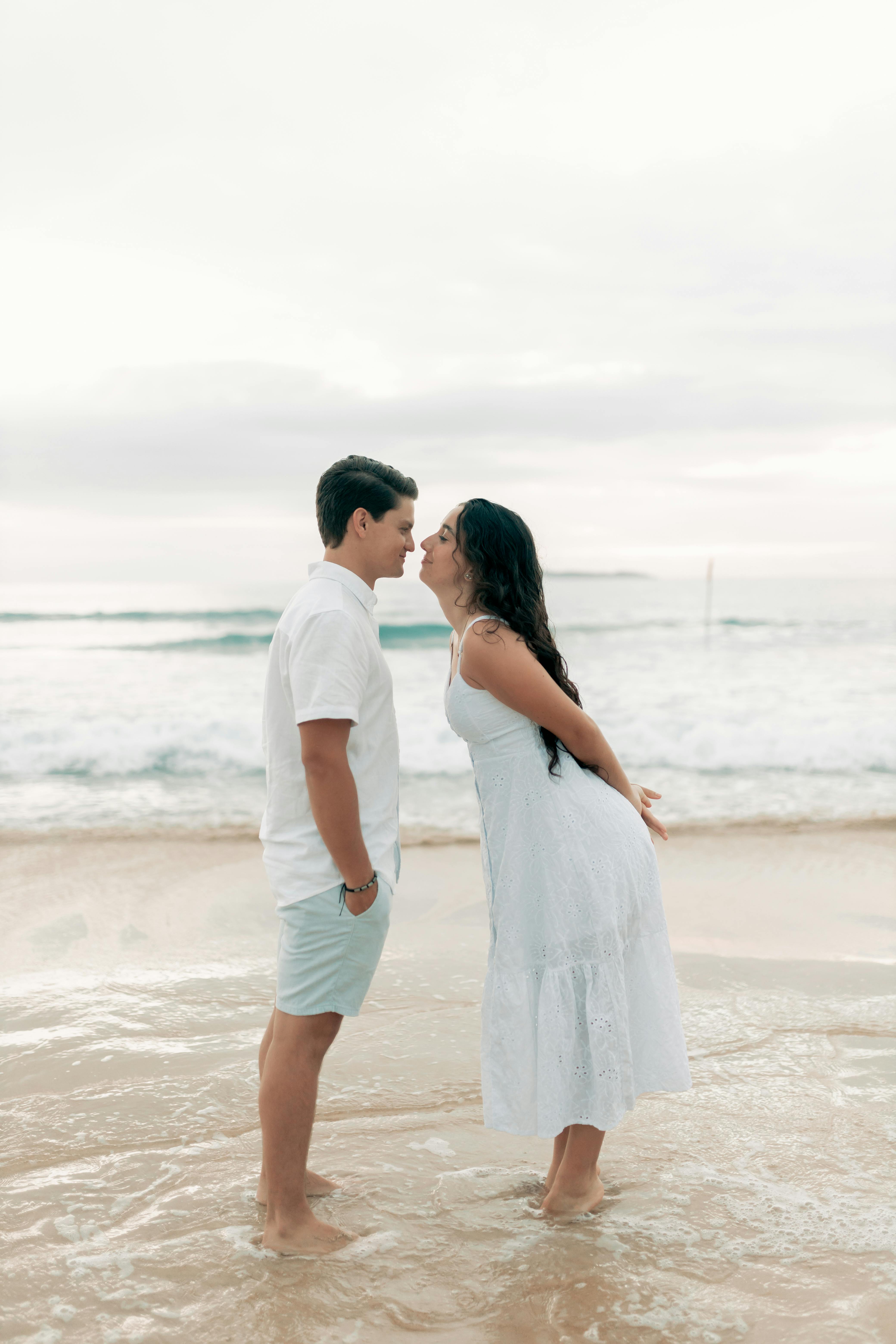 A couple sharing a tender moment by the ocean, creating a soft romantic vibe.