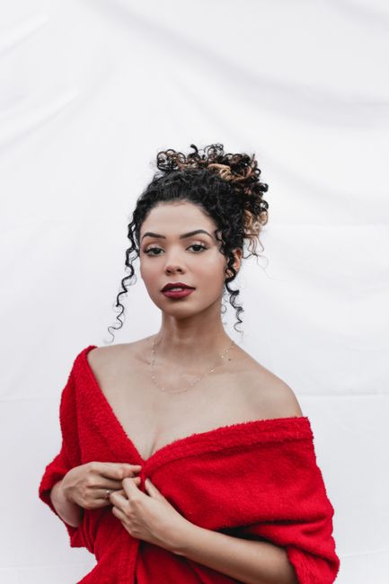 Stylish portrait of a woman with curly hair in a red off-shoulder outfit, showcasing beauty and elegance.