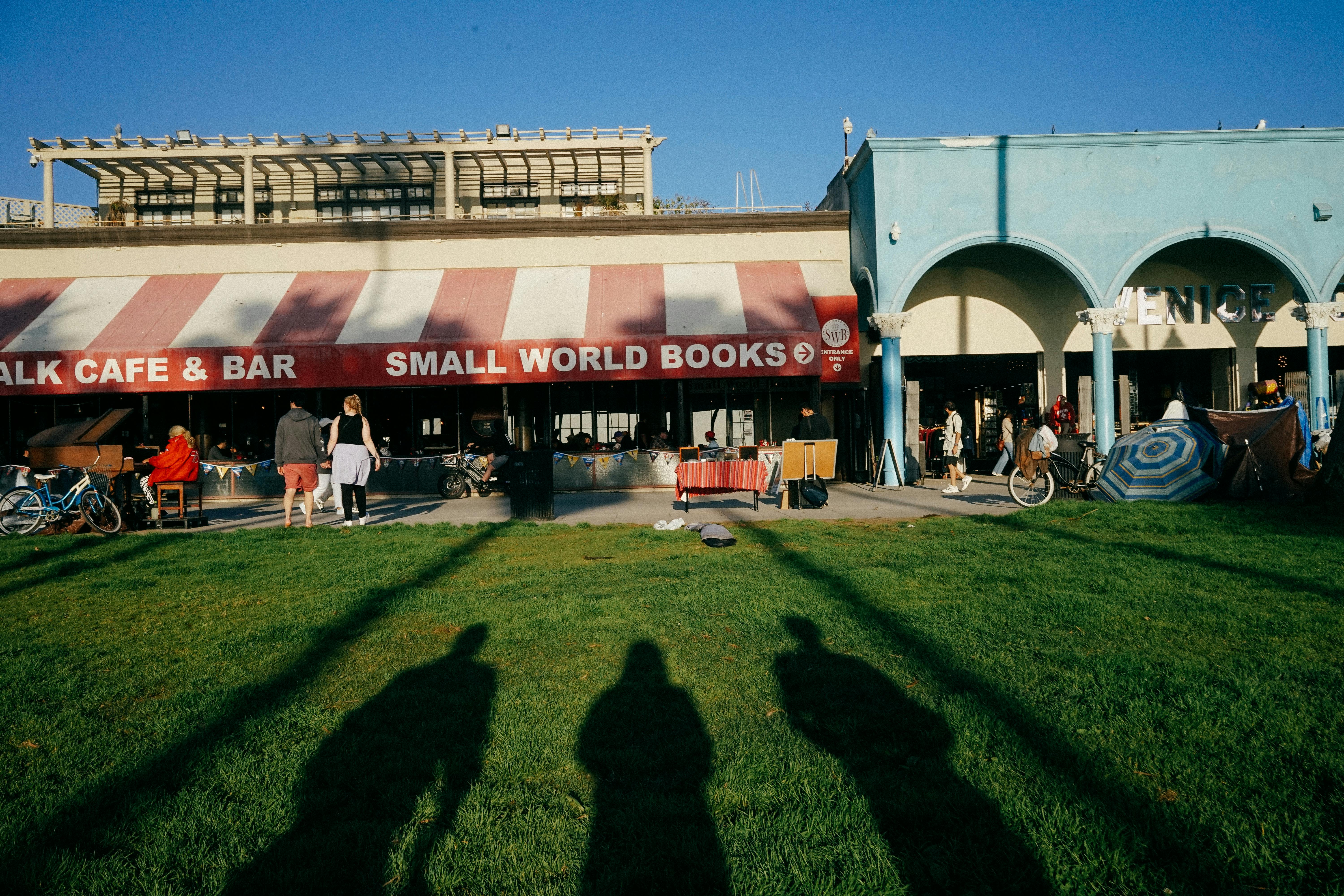 Sunlit Venice Beach scene with cafe, bookstore, and people enjoying the outdoors