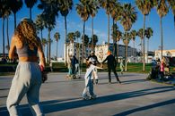Group enjoying roller skating under palm trees in Venice Beach park, California.