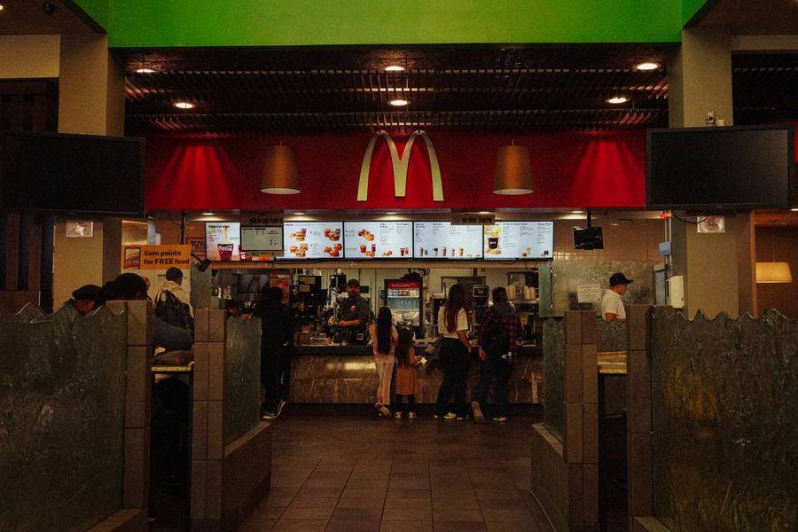 Balcão de atendimento de uma unidade do McDonald's com clientes e equipe durante o movimento
