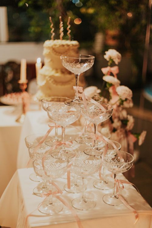 Free Champagne glasses stacked elegantly for celebration with a cake and floral decor. Stock Photo