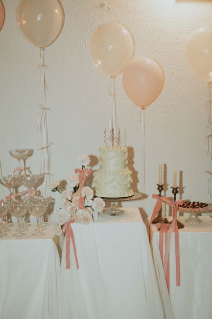 Vintage-themed party setup with cake, balloons, and floral decorations in soft pastels.