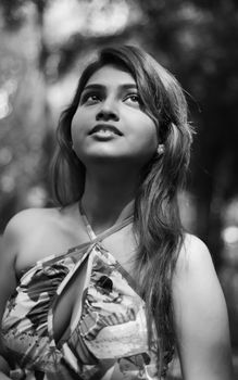 Monochrome portrait of a South Asian woman outdoors with a natural forest backdrop.