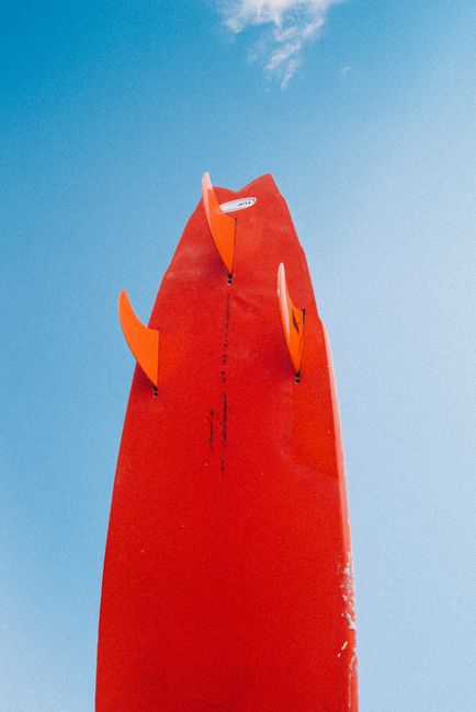 Upward view of a vibrant red surfboard with fins in Tofino