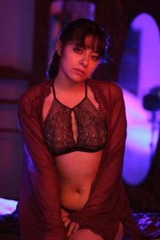 Sensual portrait of a woman in lingerie, bathed in vivid pink and purple lighting.