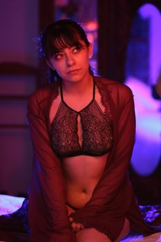 Artistic portrait of a woman in lingerie under moody lighting indoors.