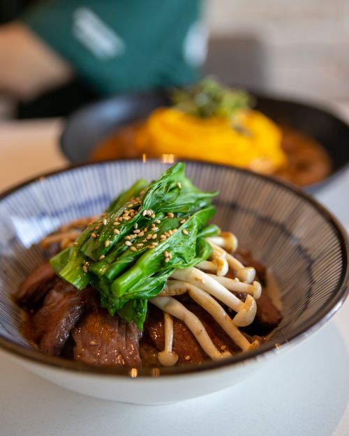 Free Close-up of a flavorful Asian beef noodle bowl topped with greens and mushrooms, perfect for food lovers. Stock Photo