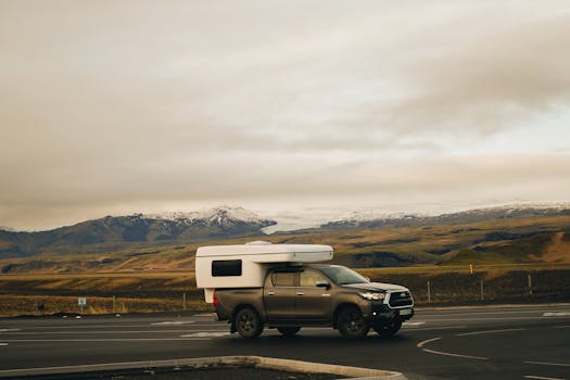 Campervan parked on a scenic highway with mountains in the background, ideal for adventure travel imagery.