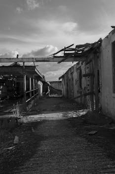 一张黑白照片中，呈现出一座腐烂废弃的工业建筑，气氛阴沉