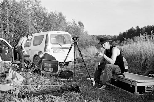 Man in Hat Sitting on Road Case