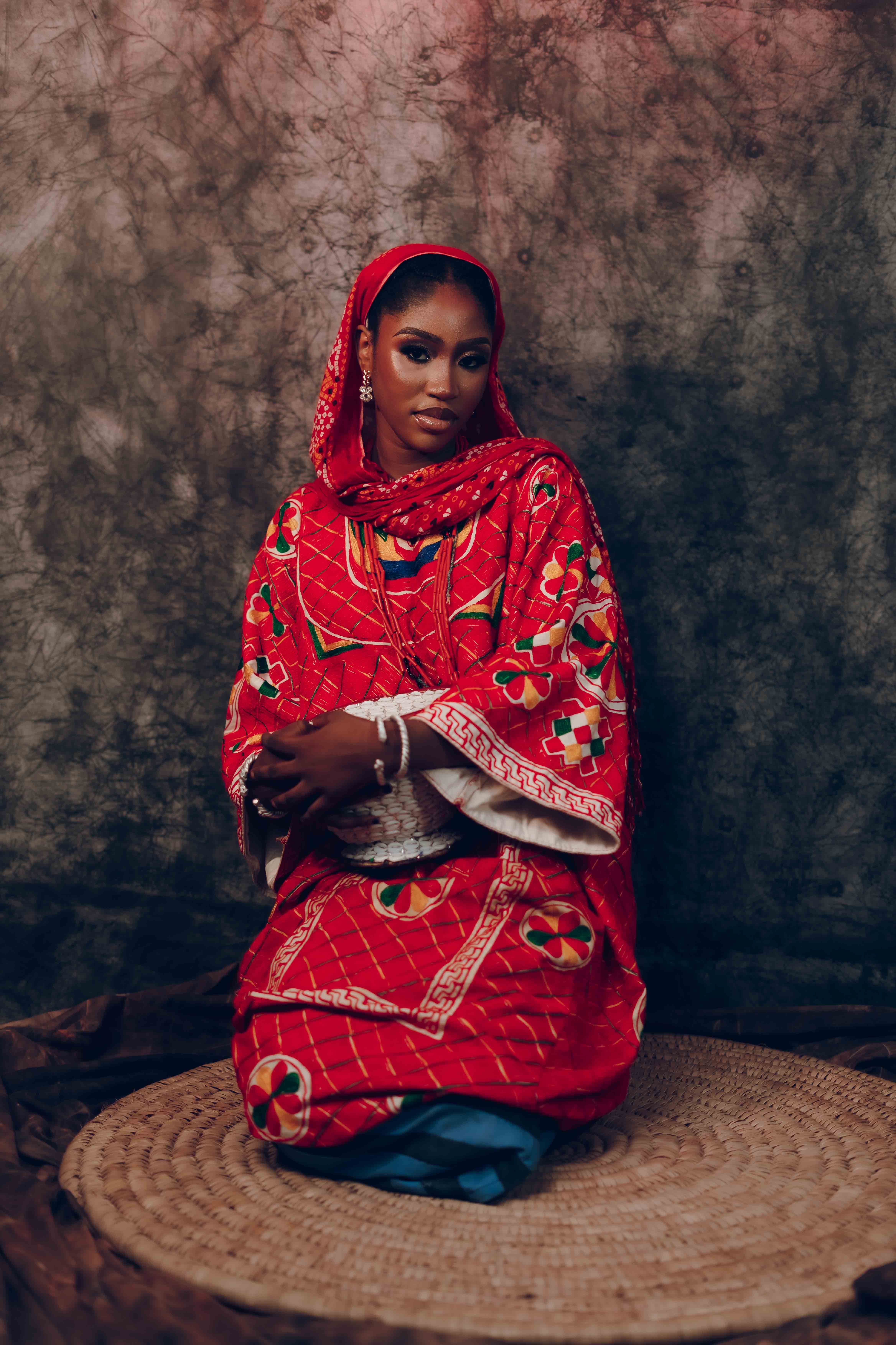Woman in Traditional Red Attire Sitting on Mat · Free Stock Photo