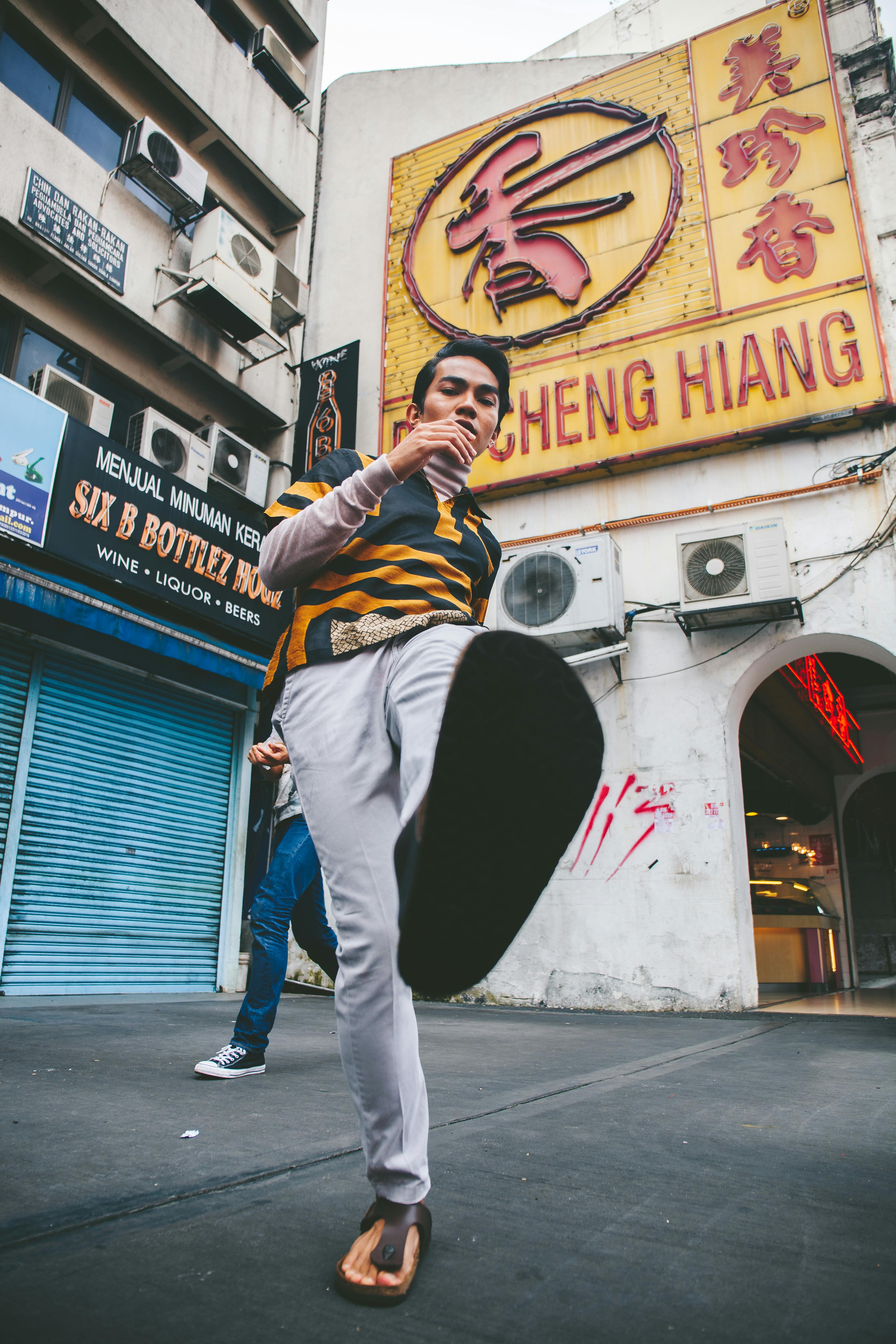 一位亚洲男子在城市环境中摆出充满活力的姿势，展示时尚的创意街头照片