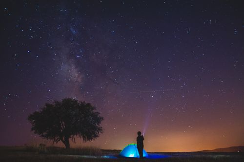 Free A person camping under a starry sky with the Milky Way visible. Stock Photo