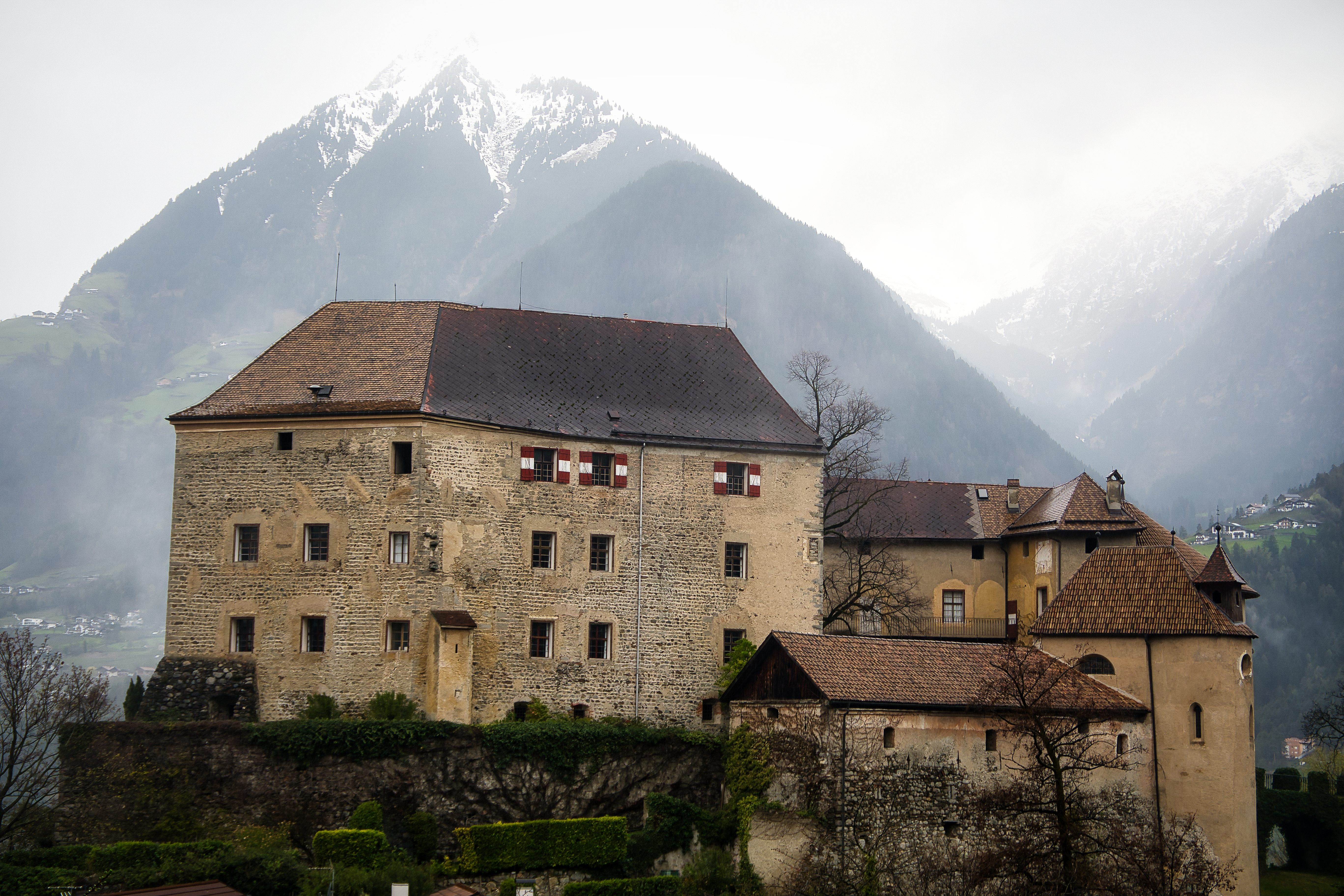 A picturesque castle in Schenna, Italy, set against majestic alpine mountains.