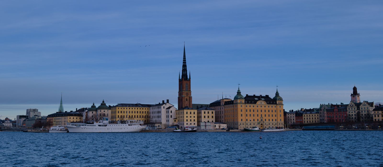 Skyline of Stockholm with historic architecture reflecting on water under a clear sky. — flights from Helsinki to Stockholm