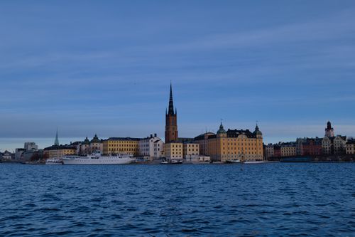 Skyline of Stockholm with historic architecture reflecting on water under a clear sky.