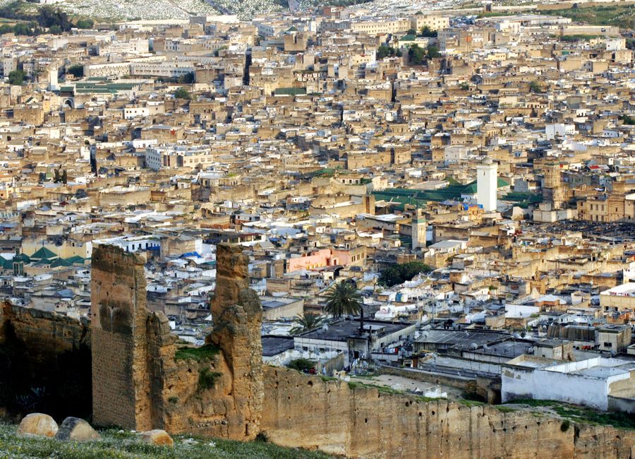 A scenic aerial view of the densely packed historic cityscape of Fès, Morocco under a clear sky.