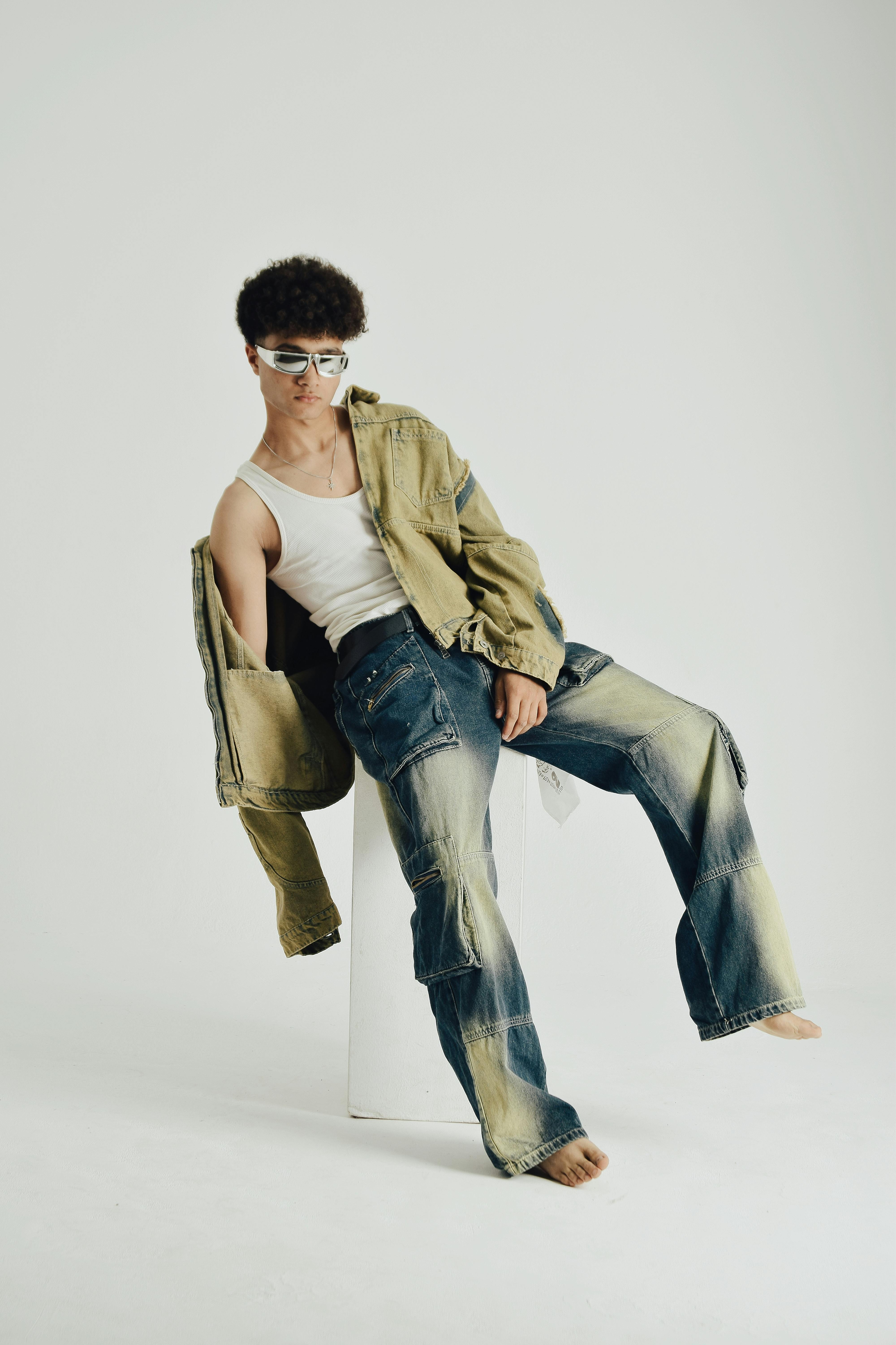 A fashion-forward young adult posing indoors wearing distressed denim and a casual top.