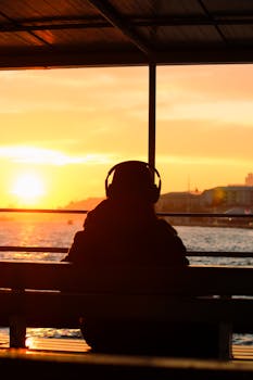 Silhouette of a person with headphones during a stunning Istanbul sunset over the water.