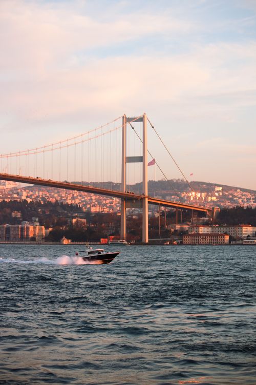 Free Capture of the Bosphorus Bridge during golden sunset with a dynamic boat on the water. Stock Photo
