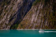 一艘游轮穿过风景优美的阿拉斯加峡湾，高耸的悬崖展现了大自然的壮丽