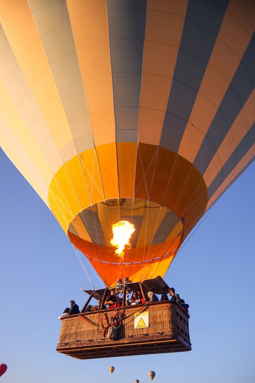 Free Colorful hot air balloon flying in clear sky with passengers enjoying the view. Stock Photo