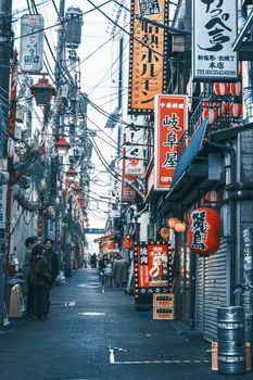 Busy urban street in Tokyo filled with colorful neon signs and people walking.